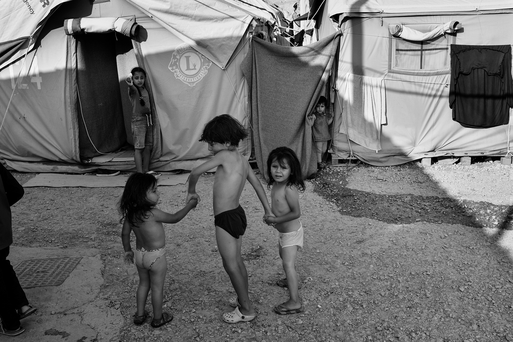 Children walking hand-in-hand inside refugee camp Moria, lesbos, Greece